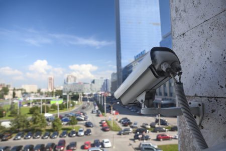 Video surveillance camera on wall looking at street parking zone